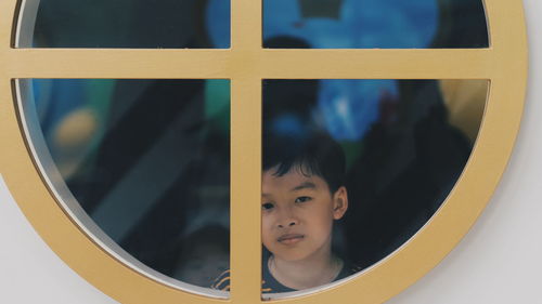 Portrait of boy looking through window