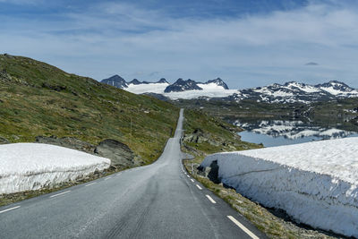 Road amidst snowcapped mountains against sky