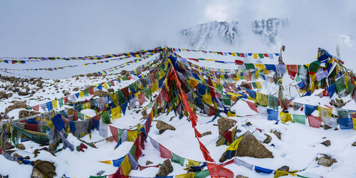 Multi colored flags on snow covered mountain against sky