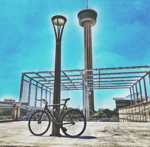 Bicycle parked by street light against sky