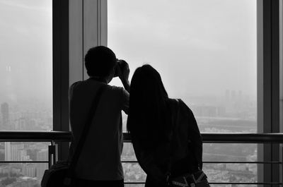 Rear view of couple looking through window