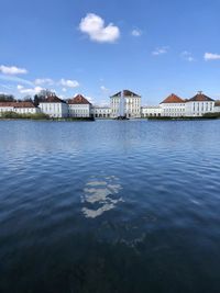 Buildings by river against sky