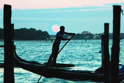 Gondolier on gondola sailing on sea