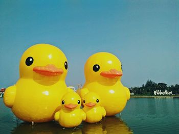 Close-up of yellow toys floating on lake against sky