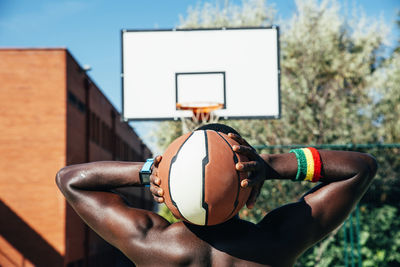 Rear view of man holding ball against basketball hoop