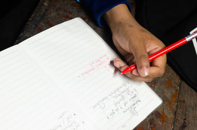 High angle view of hand holding book on table