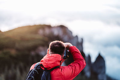 Rear view of man photographing against sky