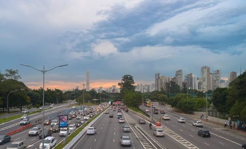 Vehicles on road against cloudy sky