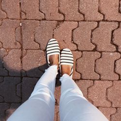 Low section of man standing on cobblestone footpath