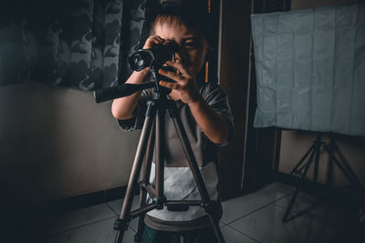 Boy using binoculars while standing on floor at home