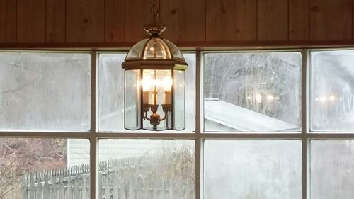 Close-up of illuminated light bulb hanging in window