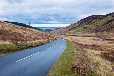 Country road against cloudy sky