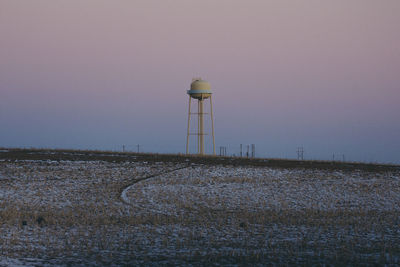 Lighthouse on field against clear sky