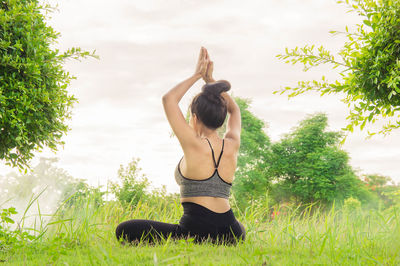 Woman doing yoga while sitting on grassy field