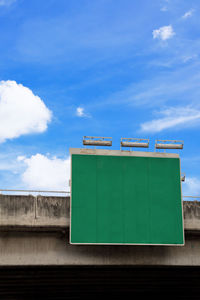 Low angle view of billboard against blue sky