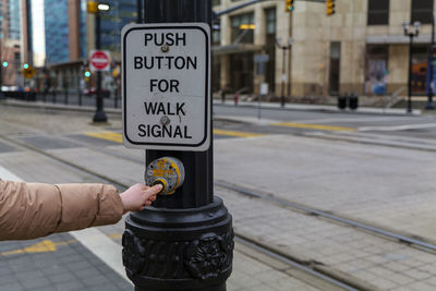 Woman hand on pedestrian sign and push button to cross railroad in jersey city