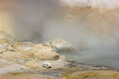 Scenic view of steam emitting geyser against sky