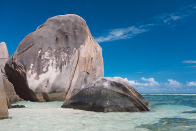 Rock formation in sea against blue sky