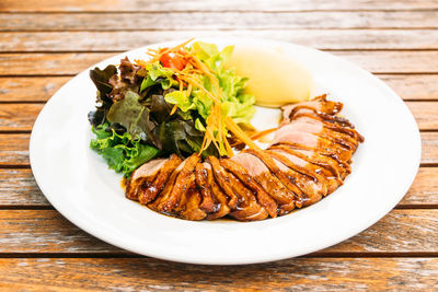 High angle view of roasted meat and salad in plate on table