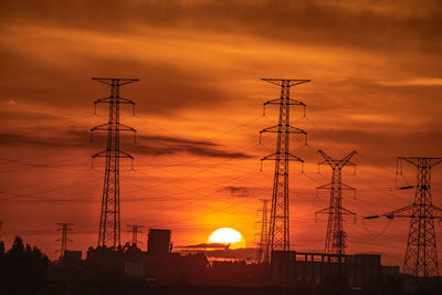 Low angle view of silhouette electricity pylon against romantic sky