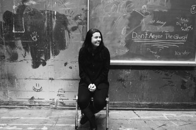 Portrait of young woman standing against wall