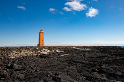 Lighthouse by sea against sky