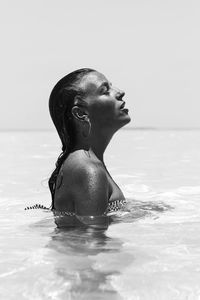 Side view of woman in water against sky