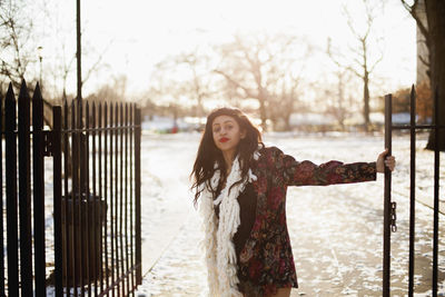 Stylish young woman swinging on a park gate in winter