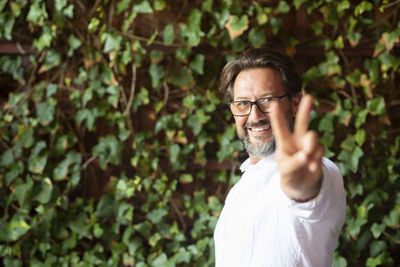 Portrait of smiling man gesturing against plants