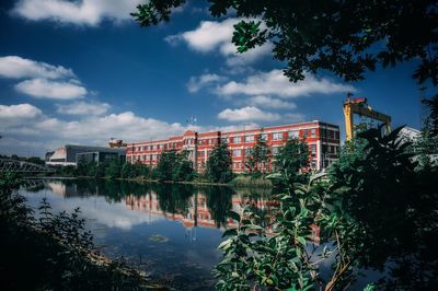 Reflection of trees and buildings in lake against sky