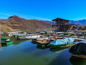 Boats moored in lake by buildings against sky