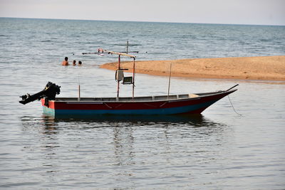 Fishing boat moored in sea against sky