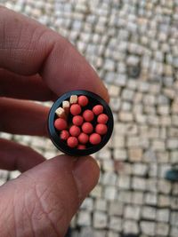 Close-up of hand holding matchsticks in container at footpath