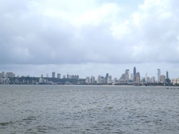Sea by buildings against sky in city