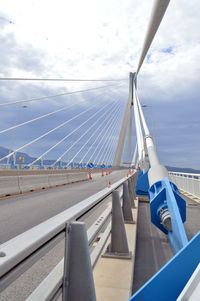 Suspension bridge in city against sky