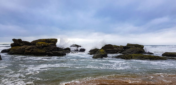 Rock formation on beach against sky