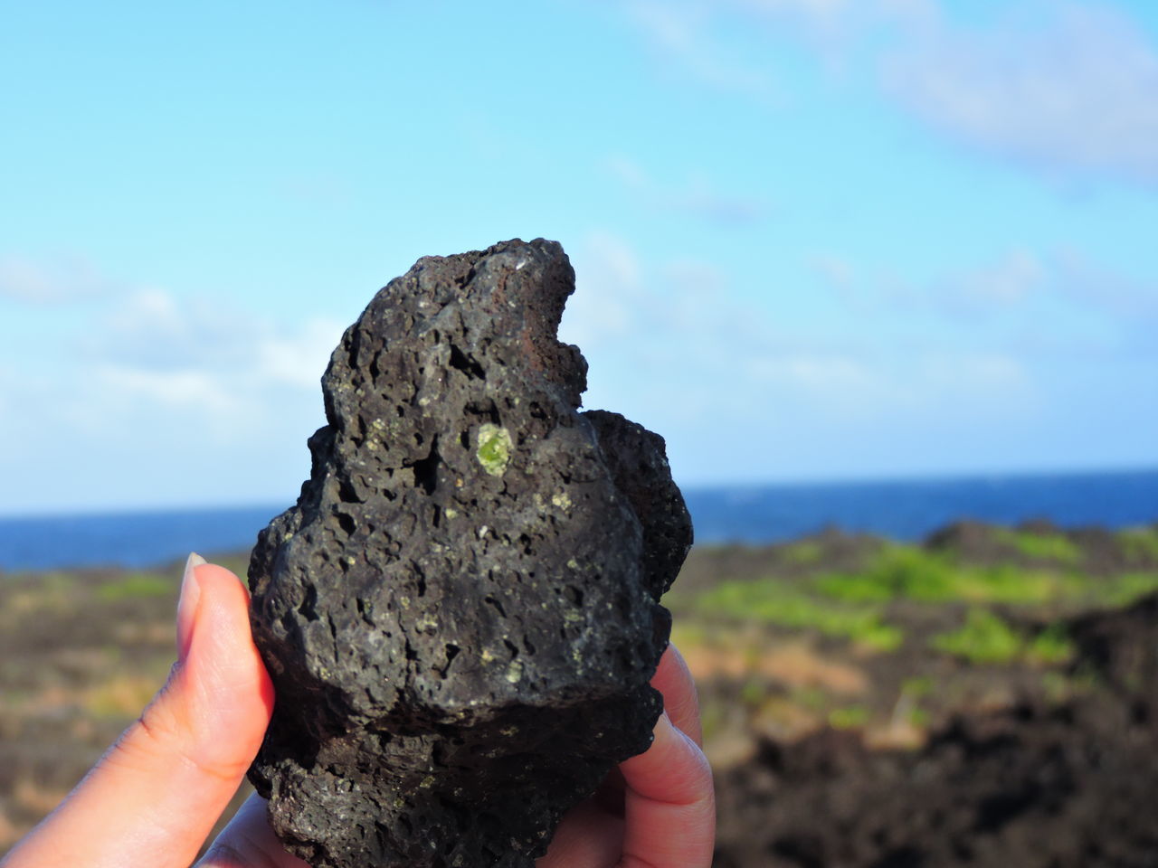 CLOSE-UP OF HAND HOLDING ROCK IN SEA