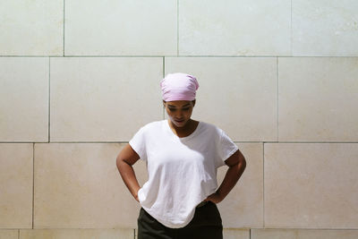 Young man looking away while standing against wall