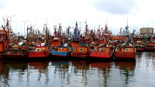 Boats moored at harbor against sky