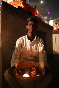 Portrait of young man holding basket at night