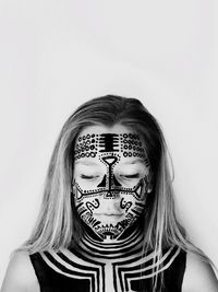 Portrait of young woman wearing face paint against white background