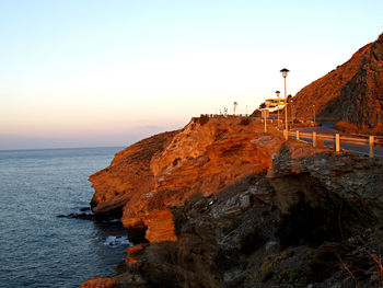 Rock formations by sea against clear sky