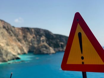 Close-up of road sign against sea and clear sky