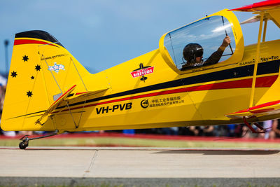 Yellow airplane on runway against sky