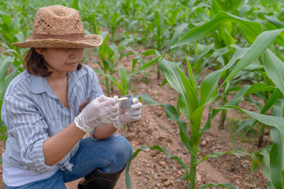 Side view of young woman standing amidst plants