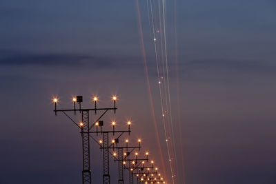 Low angle view of illuminated street lights against sky at sunset