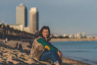 Portrait of young woman at beach against sky