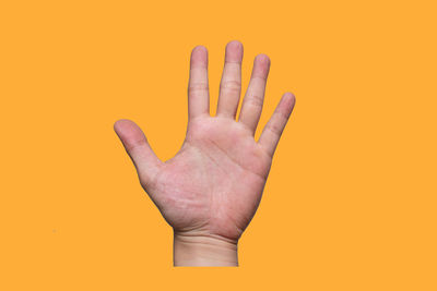 Close-up of human hand against orange background