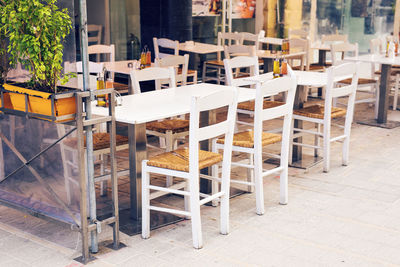 Empty chairs and tables in cafe amidst buildings in city