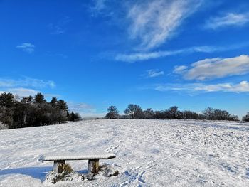 Snow covered field against blue sky